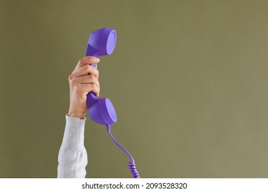 Close up of person hold handset isolated on green studio background for communication or conversation. Landline telephone call for customer service support. Feedback and helpline concept.
