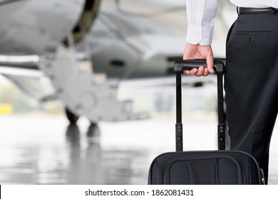 Close up of a person holding the handle of a travel bag and a flight in the background - Powered by Shutterstock