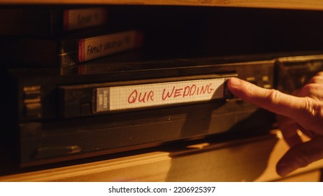 Close Up Of A Person Inserting A VHS Cassette In A Player With Nostalgic Wedding Footage From Home Video Camera. Retro Nineties Technology. Old VCR With Shallow Depth Of Field And Bokeh.