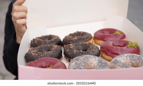 Close Up Of Person Opening A Box With Dozen Colourful Vegan Doughnuts