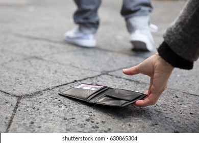 Close Of A Person Picking Up A Lost Wallet On Street