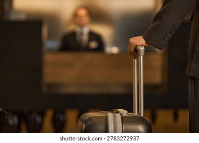 Close up of person pulling suitcase while checking in at hotel reception, representing business travel and hospitality. Ideal for tourism, corporate trip, lodging ads