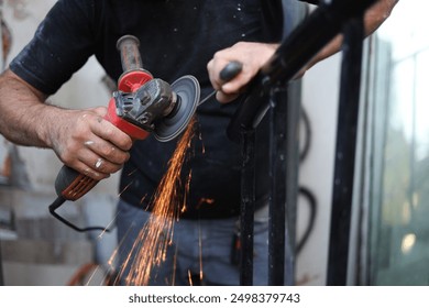 a close up of a person using an angle grinder to polish a pice of metal.sparkls fly from the point of contact.the worker is holding the grinder with one hand and stabilizing the metal with the other. - Powered by Shutterstock