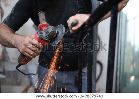a close up of a person using an angle grinder to polish a pice of metal.sparkls fly from the point of contact.the worker is holding the grinder with one hand and stabilizing the metal with the other.