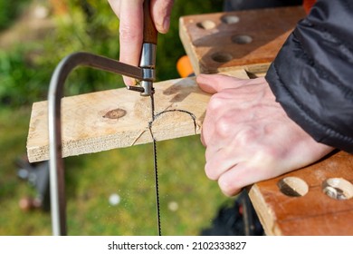 Close up of a person using a coping saw to cut a semi circle out of a plank of wood. DIY, construction, home improvement concept - Shutterstock ID 2102333827