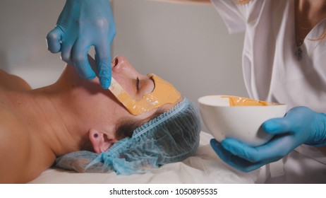 Close Up Of A Person Who Visiting The Beauty Salon, Fruit Mask Is Applied On The Face With A Special Wooden Stick