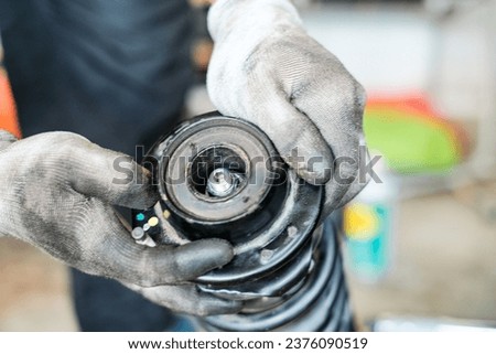 A close up of a person working at the workshop. Shock absorber with a spring and bearing assembly