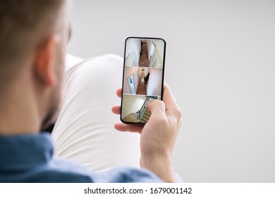 Close Up Of A Person's Hand Using Home Security System On Mobile Phone