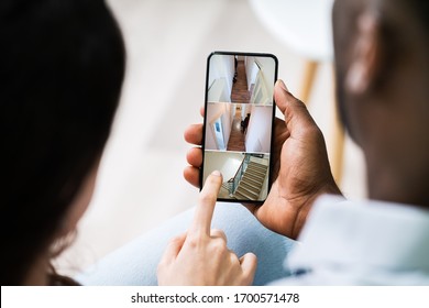 Close Up Of A Person's Hand Using Home Security System On Mobile Phone