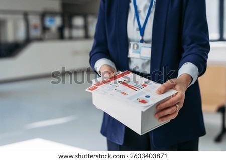 Close up of pharma rep holding box with samples of new medication and flyer.
