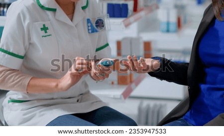 Close up of pharmacist in chemist store using medical diabetes examination tool to check patient glucose levels in blood. Expert and client in annual exam, doing checkup to preventing hypoglycemia