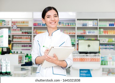 close up pharmacist with with smile on face making notes in drug store