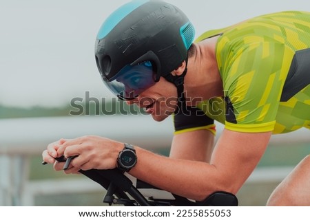 Close up photo of an active triathlete in sportswear and with a protective helmet riding a bicycle. Selective focus Foto stock © 