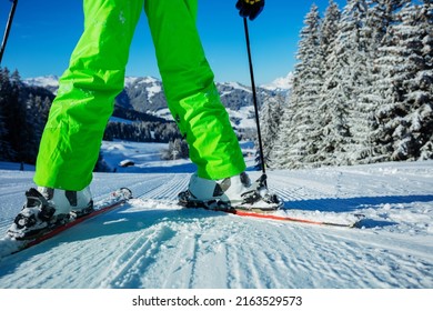 Close photo of the alpine skier with focus on the ski between legs stand on the track over beautiful snowy forest after snowfall on background