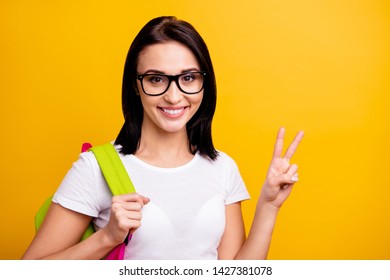 Close up photo amazing she her lady hold arm hand school colored study modern cool backpack v-sign symbol say hi positive friendly wear specs casual white t-shirt isolated bright yellow background