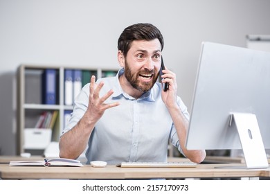 Close Up Photo. Angry And Annoyed Office Worker. He Talks On His Mobile Phone, Shouts. Sitting At A Computer Desk.