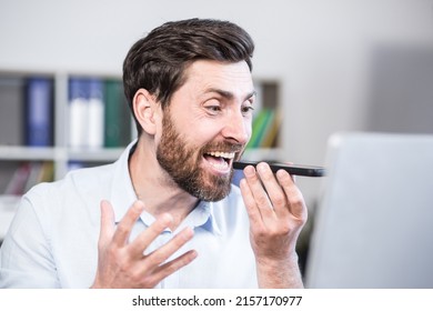 Close Up Photo. Angry And Annoyed Office Worker. He Talks On His Mobile Phone, Shouts. Sitting At A Computer Desk.