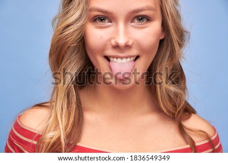 Close up photo of attractive funky carefree girl stick tongue out of mouth playful girls in red clothes with yellow stripes on blue background