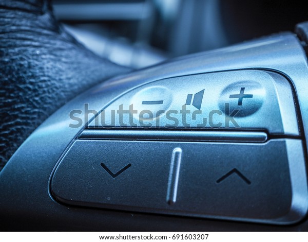 Close up photo of audio /voice\
volume control buttons on the steering wheel of a modern\
car