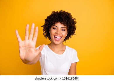 Close up photo beautiful amazed she her dark skin lady glad arms hands five fingers raised show countable uncountable things lesson wearing casual white t-shirt isolated yellow bright background