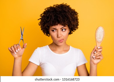 Close up photo beautiful amazing she her dark skin lady hold hair brush scissors hands pros cons ready change herself style wear casual white t-shirt isolated yellow bright vibrant vivid background