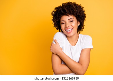 Close up photo beautiful amazing she her dark skin lady adorable remember best date ever imagination hug herself eyes closed wear casual white t-shirt isolated yellow bright vibrant background