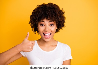 Close up photo beautiful amazing she her dark skin lady arms hands finger thumb up approve quality advising buy buyer wearing casual white t-shirt isolated yellow bright vivid background