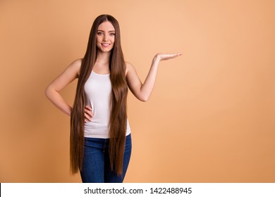 Close up photo beautiful her she lady very long brown hair open arm hand empty space recommend buy buyer new hairdress styling balm wear casual tank-top jeans denim isolated pastel beige background