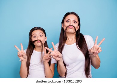 Close up photo beautiful two people brown haired mom small little daughter make funky moustache curls like guys man male showing v-sign crazy wear white t-shirts isolated bright blue background