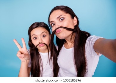 Close up photo beautiful two people brown haired mom small little daughter make take selfies moustache curls pretend guy man male show v-sign wear white t-shirts isolated bright blue background