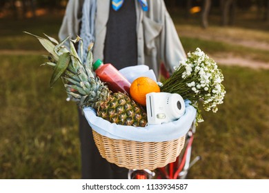 Close Up Photo Of Bicycle Basket Full Of Fruits,wildflowers And Little White Poloroid Camera In Park