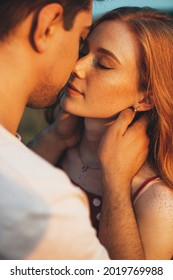 Close up photo of a caucasian ginger woman with freckles kissing and embracing in the sunshine