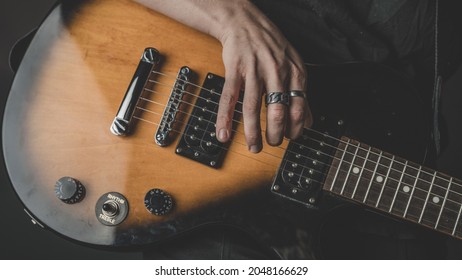 Close Up Photo Of Caucasian Woman Holding A Beautiful Brown Electric Guitar Isolated On A Black Colored Background. Female Rockstar Holding A Musical Instrument.