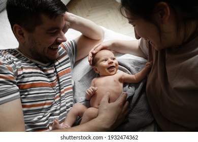 Close up photo of the cheerful caucasian parents looking at their baby with tenderness while spending time at bedroom with him. Childhood concept. Stock photo