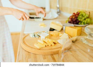 Close Up Photo Cheese Plate - Woman's Hands Cutting Different Kinds Of Cheeses In Counter At Kitchen Home Interior.