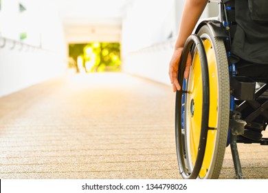 Close Up Photo Of Child Sitting On The Wheelchair In Hospital Walk Way, His Hand Controlling The Wheel, Life In The Education Age Of Children, Happy Cerebral Palsy Kid Concept.