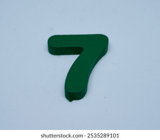 close up photo of a children's toy in the shape of the number seven, made of wood painted green - Powered by Shutterstock