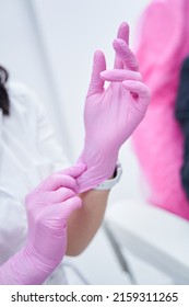 Close up photo of cosmetologist hands wearing pink nitrile gloves