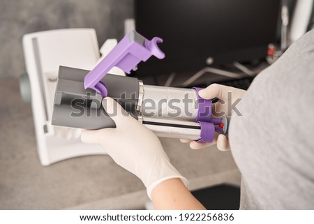 Close up photo of dental impression material mixing machine. Cropped view of the hands of female dentist holding part of impression material mixing machine before adjusting it into the machine