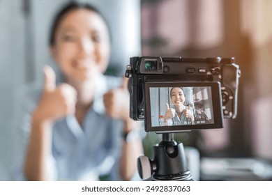 Close up photo of digital camera with young female influencer vlogger blogger online broadcasting in social media. Woman showing thumbs up sign on camera. Content maker concept - Powered by Shutterstock