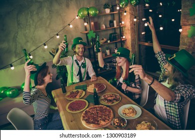 Close Up Photo Event Gathered Big Company Friends Clinking Drinks Green Bottles Hats Leaf Eat Food Pizza Sausage Chips Ireland Style Party Leprechaun Costumes Rest Relax Together Laugh Laughter