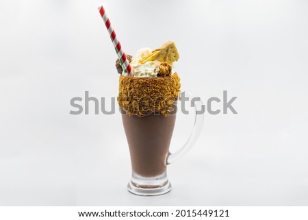 Close up photo of a fancy chocolate milkshake topped with crackers on a white background