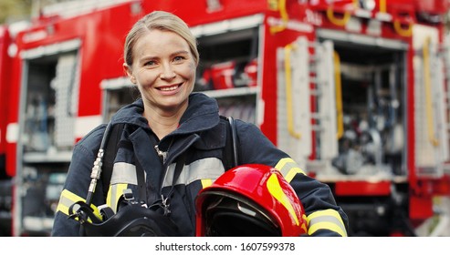 Close up photo of Female firefighter in protective suit with oxygen mask and helmet in her hands