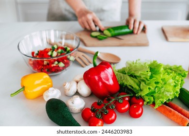 Close up photo of female hands with knife cutting fresh cucumber on the table on domestic kitchen. Many ripe, tasty and colorful vegetables with olive oil. Vegan meal, healthy nutrition - Powered by Shutterstock