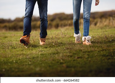 Close up photo of female and male legs in jeans and boots walking on the grass - Shutterstock ID 664264582
