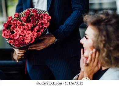 Close up photo. Focus at big red bouquet of roses, celebrating time. Man presenting flowers to woman during romantic date in restaurant. - Shutterstock ID 1517678021
