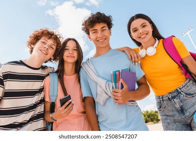 Close up photo of friends teenagers high school pupils college students with bags holding books phone gadgets spending time meeting hanging out outside in skate green nature park looking at camera - Powered by Shutterstock