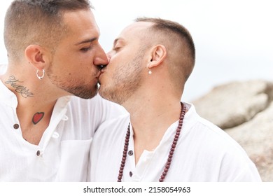 Close up photo of a gay couple kissing next to the sea