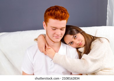 Close up photo of a girl put her head on her boyfriend shoulder embracing him and looking at the camera while boy looking down. - Shutterstock ID 2108162834