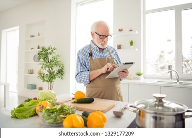 Close up photo grey haired he his him grandpa hands arms e-reader not interested in cooking watch read reader internet news bored wear specs casual checkered plaid shirt jeans denim outfit kitchen - Powered by Shutterstock